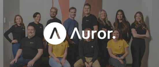 team photo of diverse individuals wearing branded shirts in an office setting, Auror team group photo with logo and branding