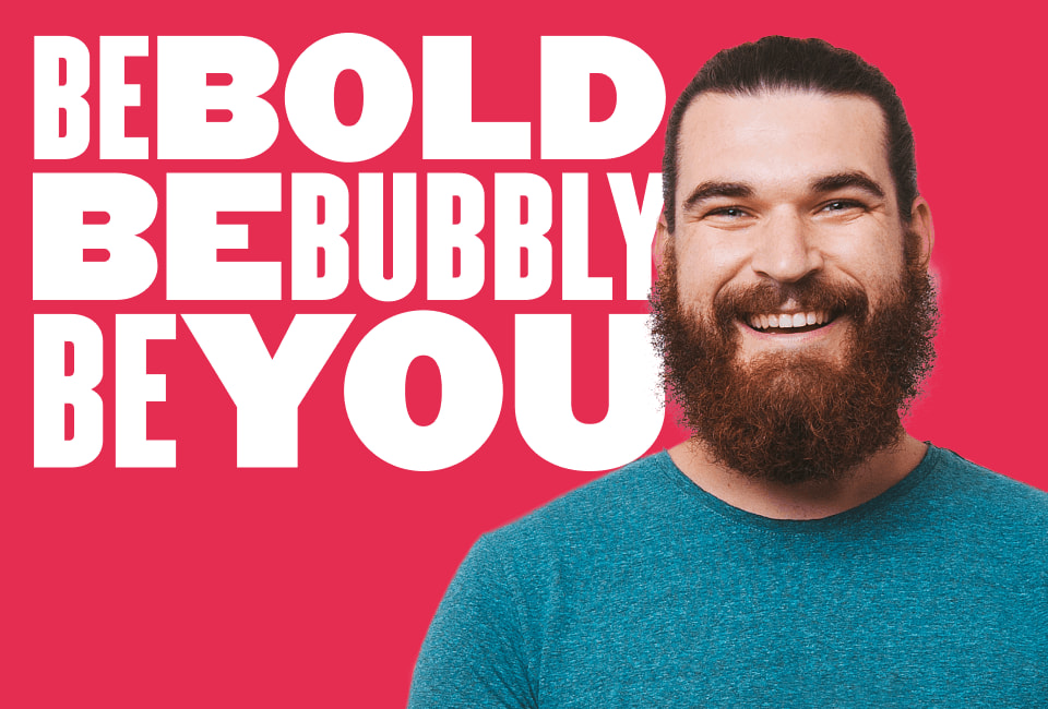 BE BOLD BE BUBBLY BE YOU phrase with smiling man in teal shirt against bright pink backdrop. Vibrant and motivational image. bold, bubbly