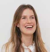 smiling woman with long hair wearing a white blouse against a light background, joyful expression and neutral setting