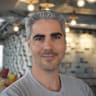 smiling man with gray hair and beard in a modern interior, soft lighting and green accents visible, portrait of a man in casual gray t-shirt