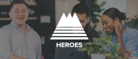 smiling colleagues collaborating over laptop, logo of HEROES with plants in a bright workspace