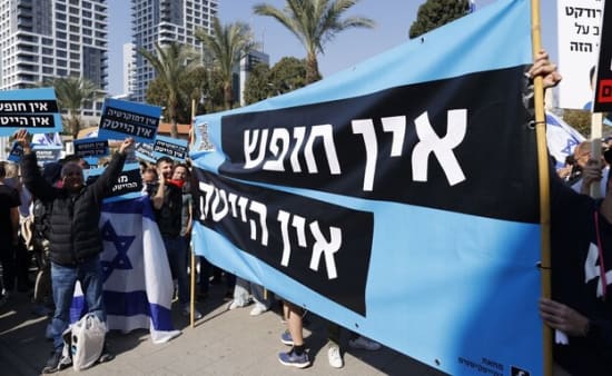אין חופש אין זכות, Protesters hold banners in Tel Aviv, showcasing political activism with Israeli flags and palm trees.