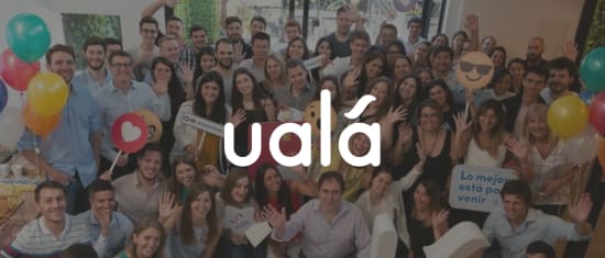 group of smiling people celebrating with colorful balloons holding signs at a lively event, Ualá team gathering expressing joy