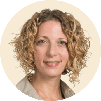woman with curly hair smiling, professional headshot on neutral background