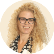 curly blonde woman with glasses smiling in a formal outfit, professional portrait with light background and circular frame