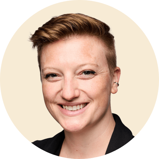 smiling person with short hair in a black jacket, round background, headshot portrait with natural expression and light skin